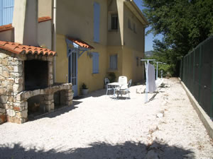 Le jardin avec barbecue, table et chaises, transats, parasol, étendoir